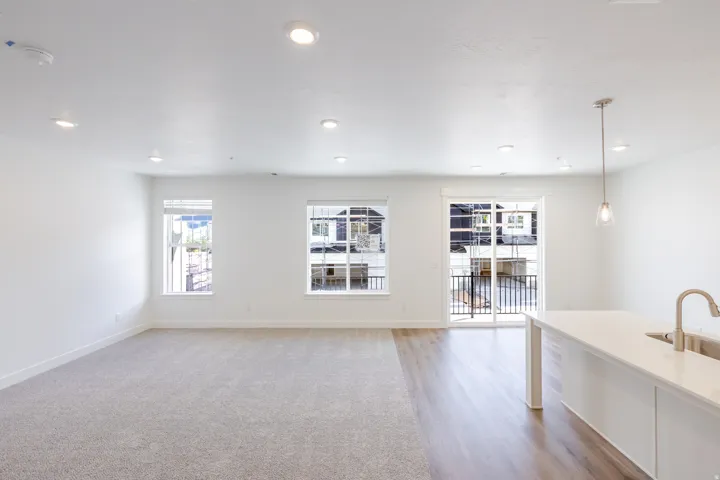 Recessed ceiling lighting, carpet flooring, wood-finish flooring, sliding glass door, kitchen island with sink and faucet