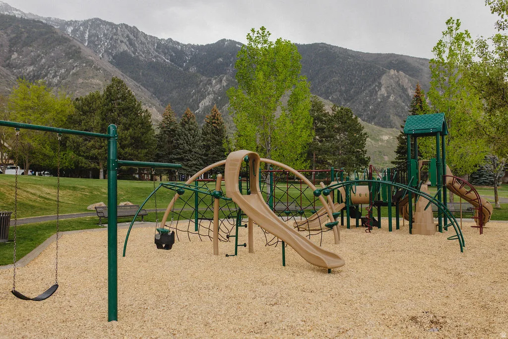 Communal playground featuring a mountain view and a lawn