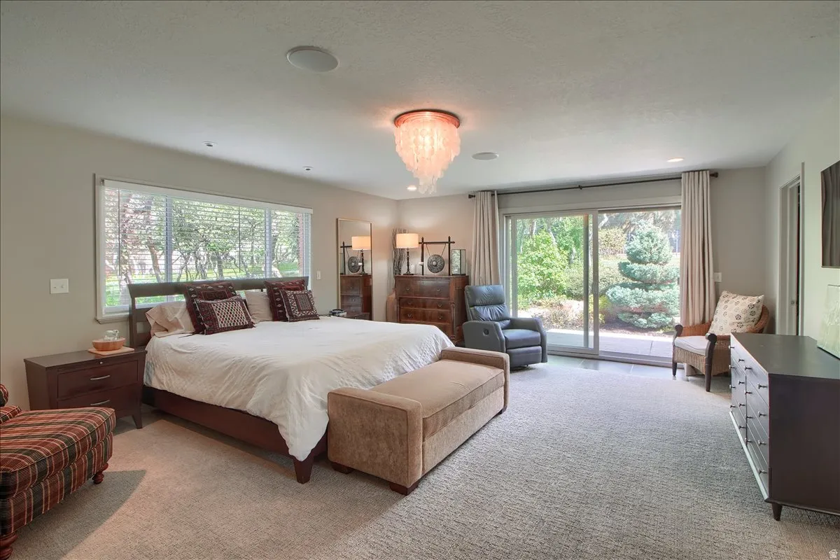 Bedroom with access to exterior, light colored carpet, and multiple windows
