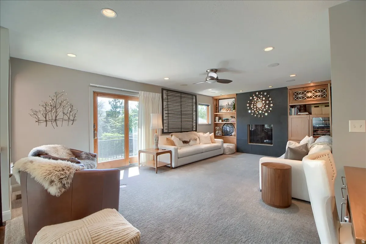 Living room featuring built in shelves, ceiling fan, carpet flooring, recessed lighting, and a tile fireplace