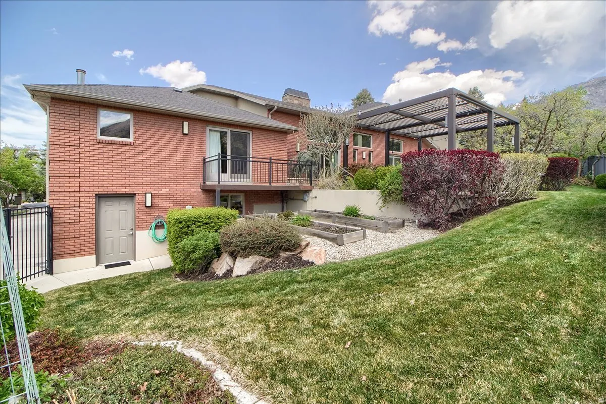 Rear view of house with brick siding, a garden, a chimney, and a balcony