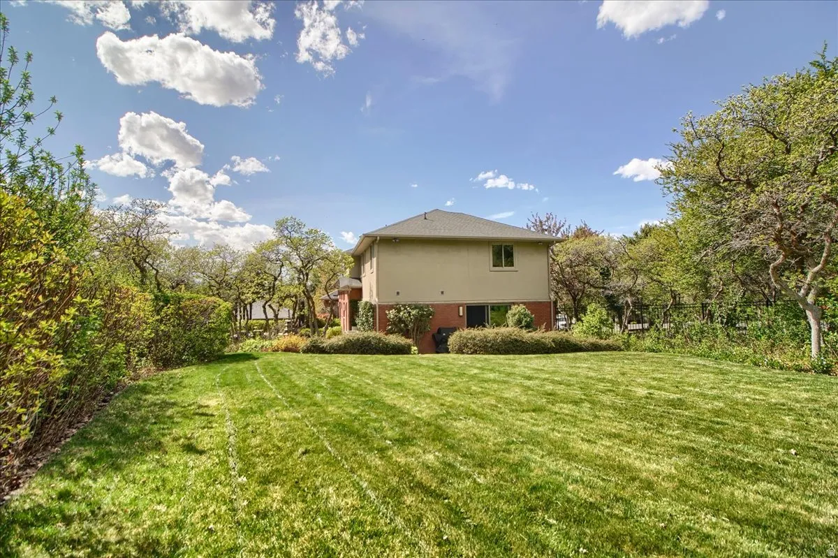 Back of property featuring view of scattered trees and brick siding