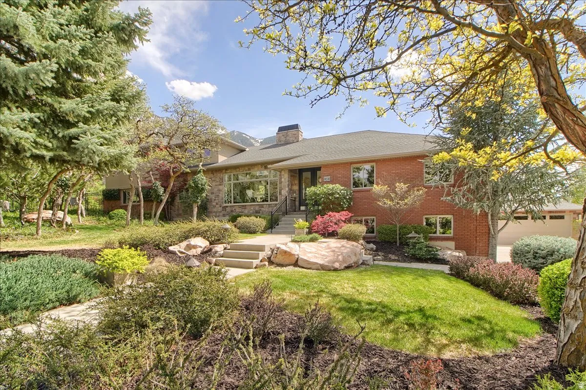 Rear view of house featuring a chimney, brick siding, and a lawn