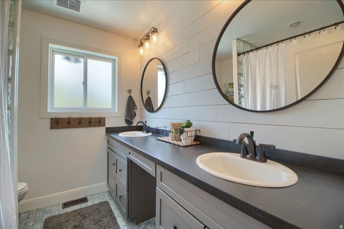 Full bath featuring curtained shower and double vanity