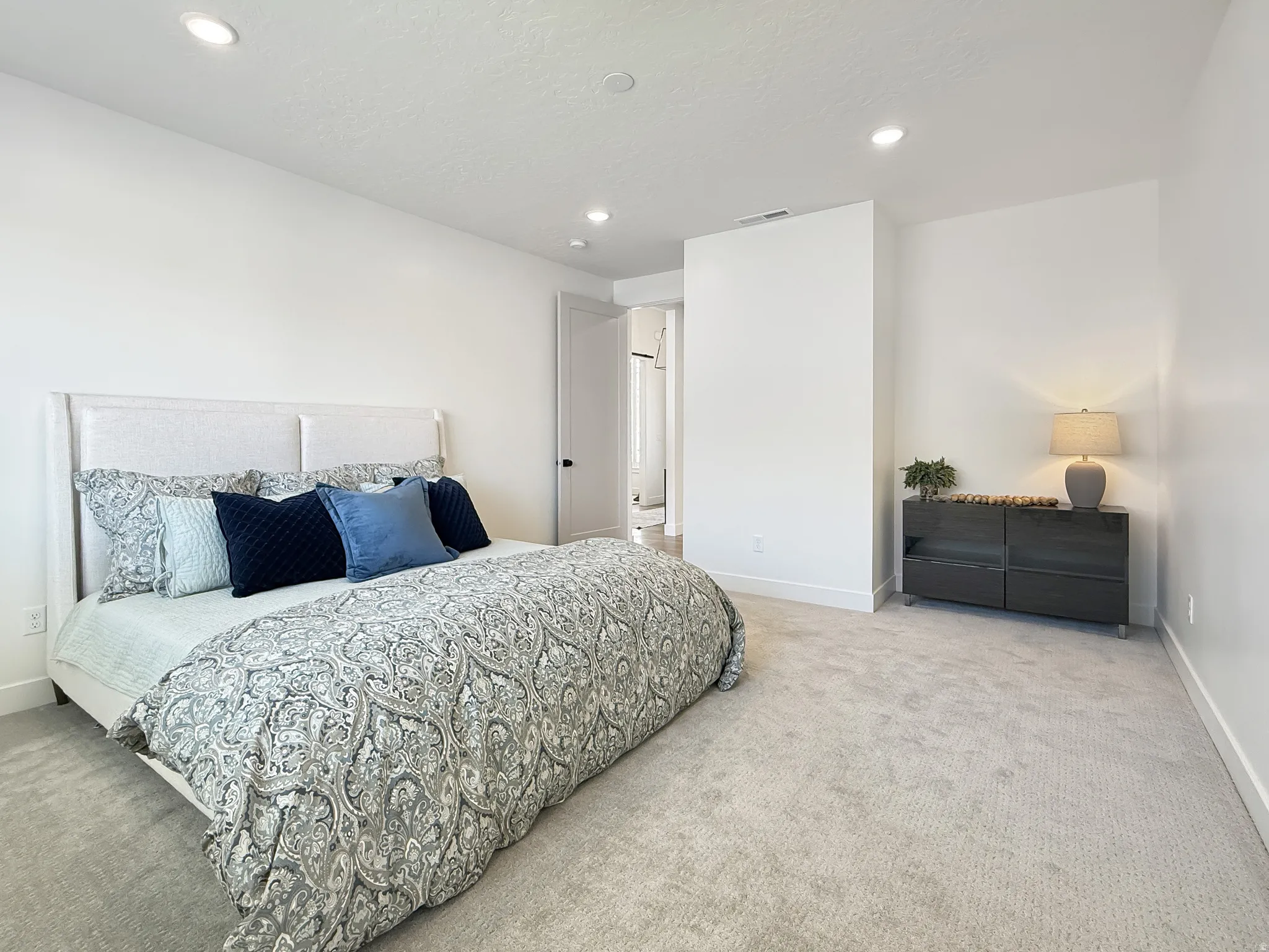 Bedroom with light colored carpet and recessed lighting