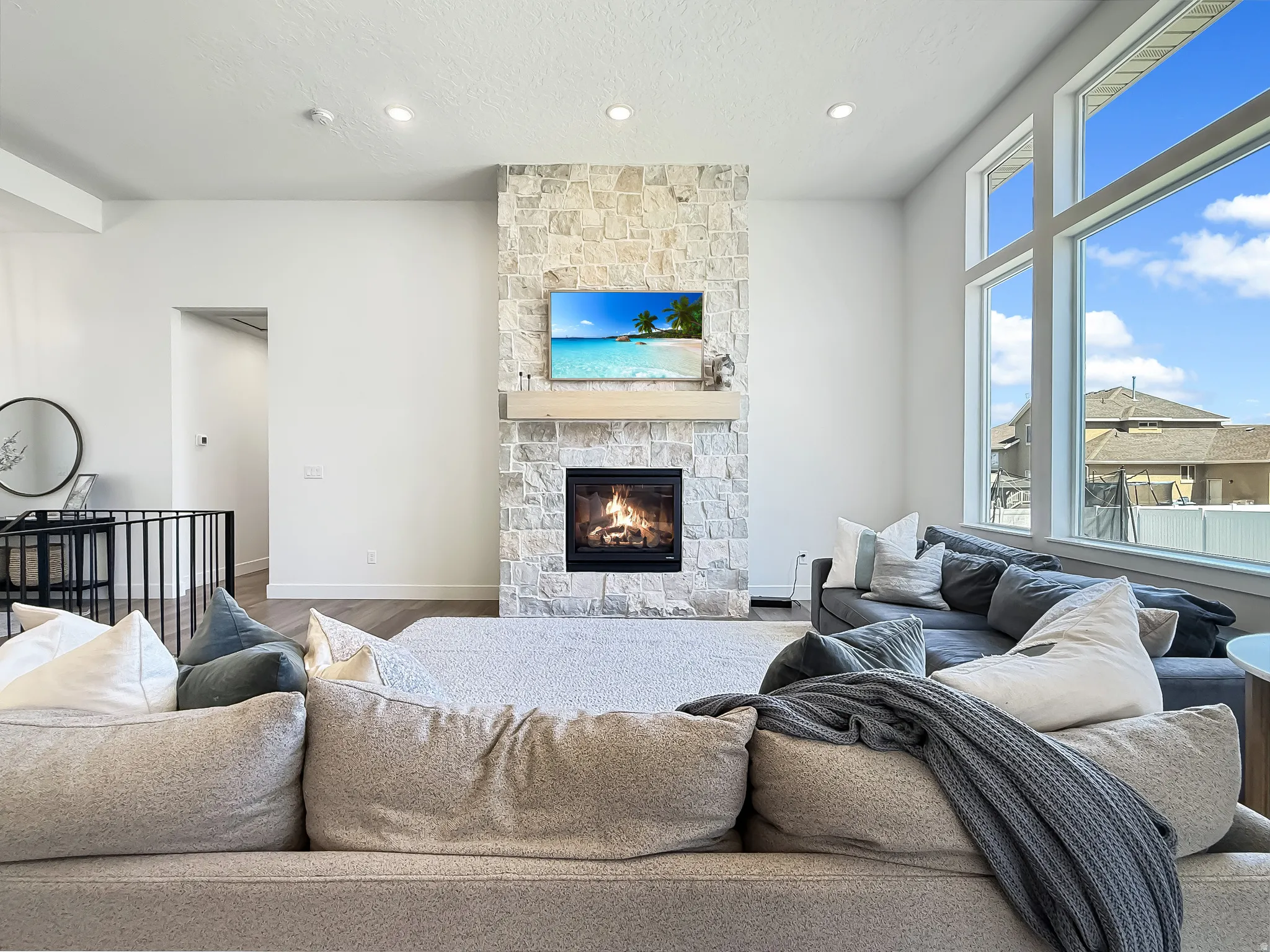Living room featuring a stone fireplace, wood finished floors, recessed lighting, and a textured ceiling