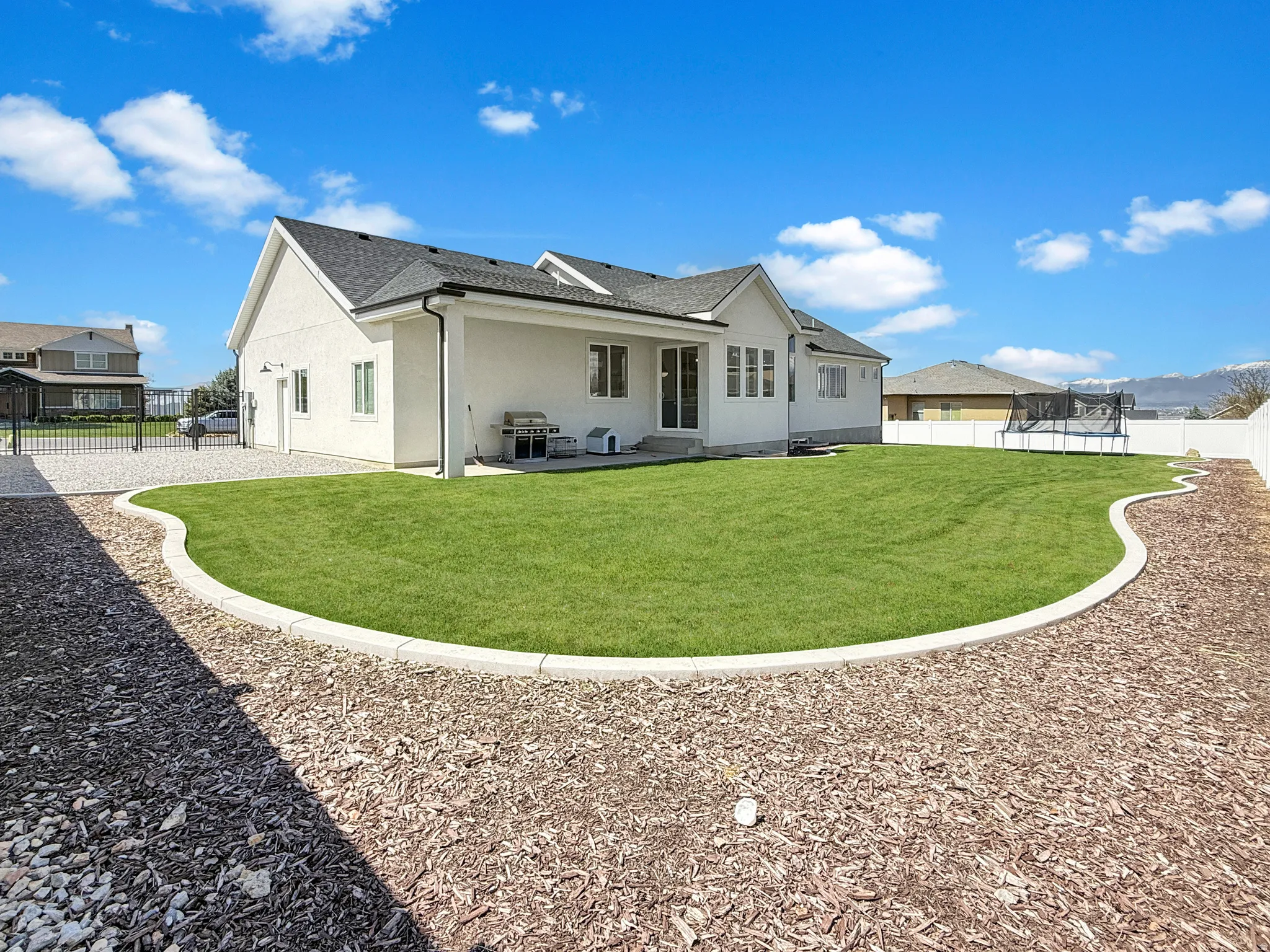 Back of house with a fenced backyard, a patio, stucco siding, a trampoline, and roof with shingles