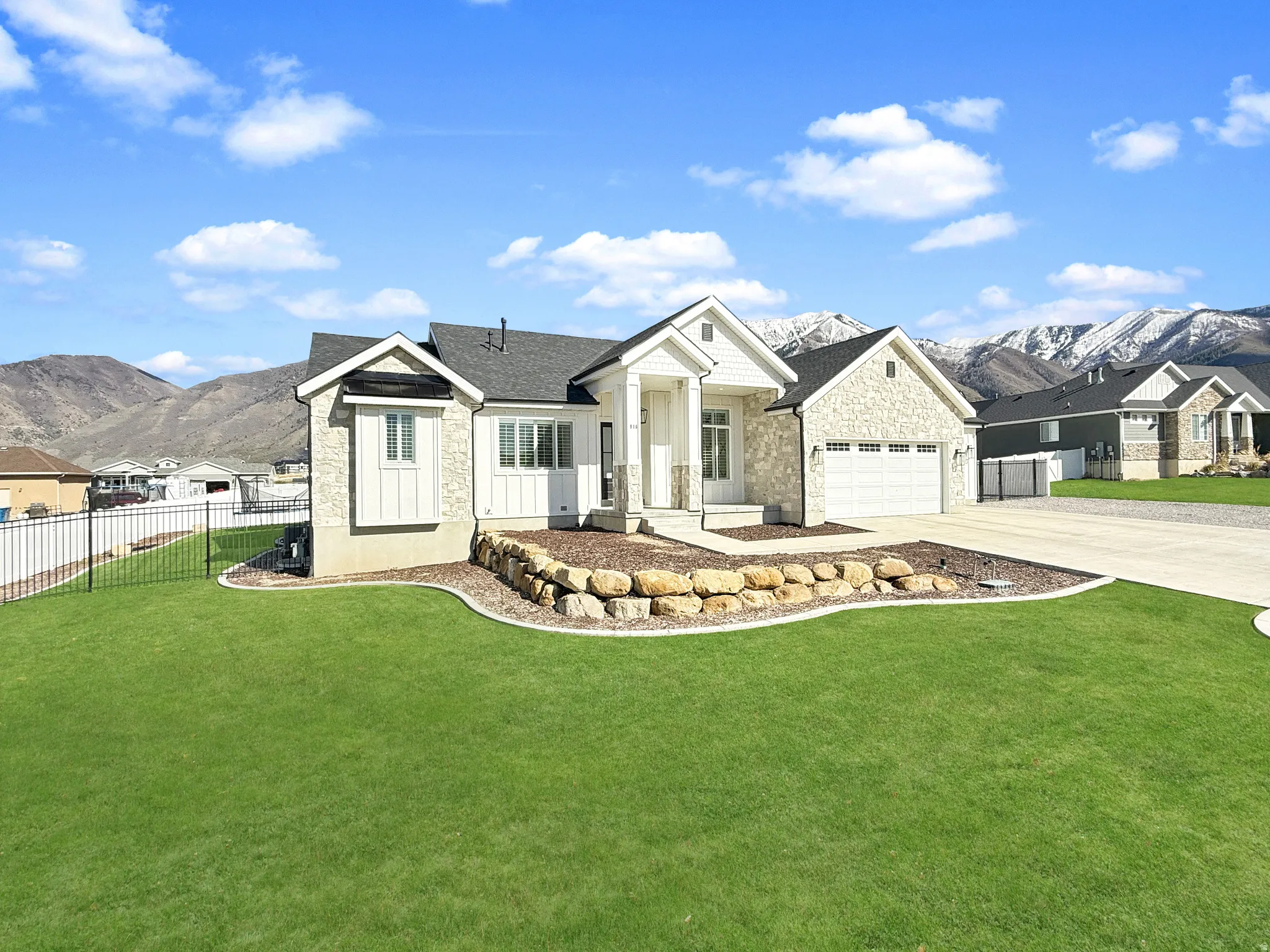 View of front of home with a mountain view, stone siding, a garage, and concrete driveway