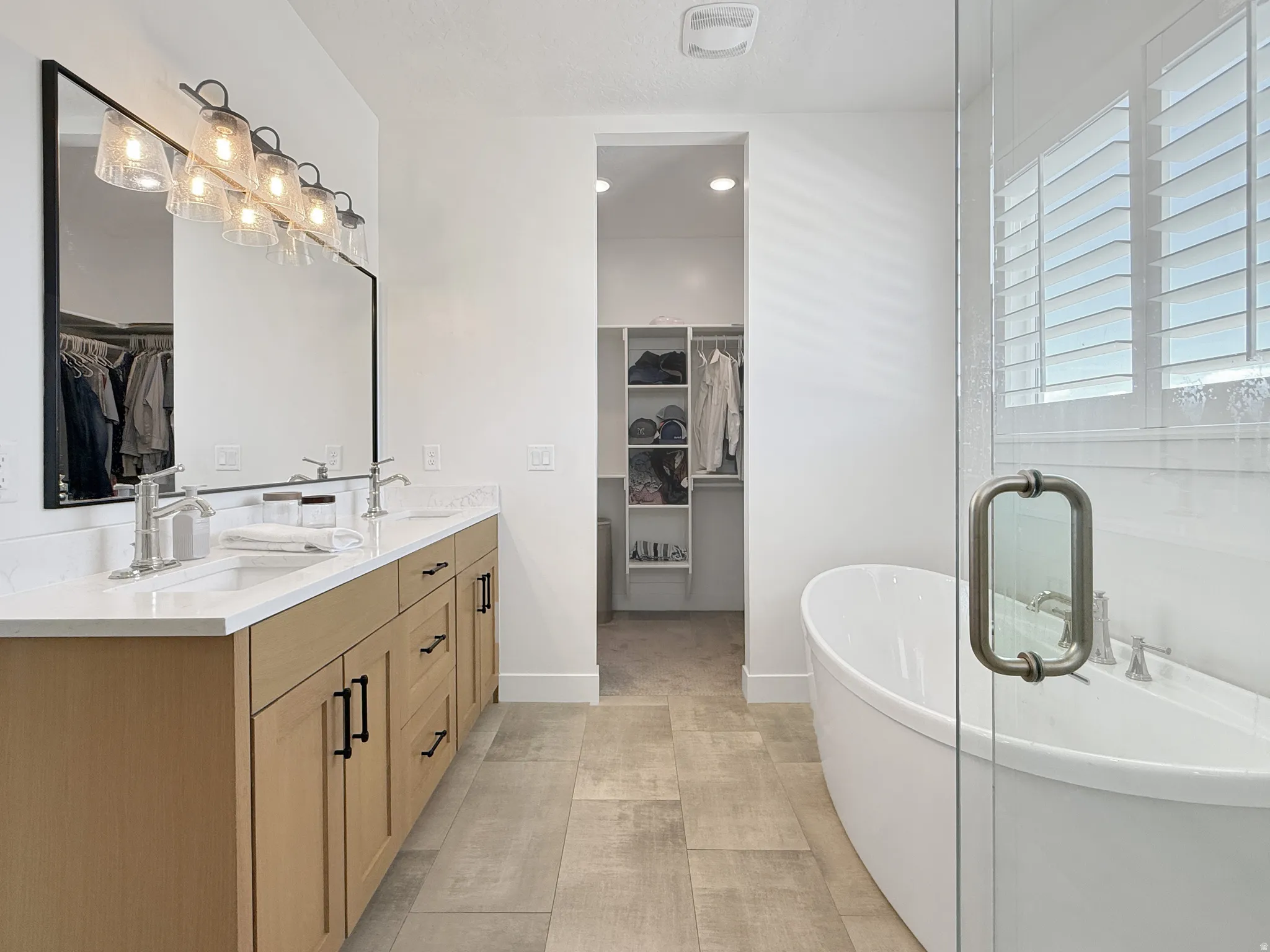 Full bath with a spacious closet, double vanity, a freestanding bath, and recessed lighting