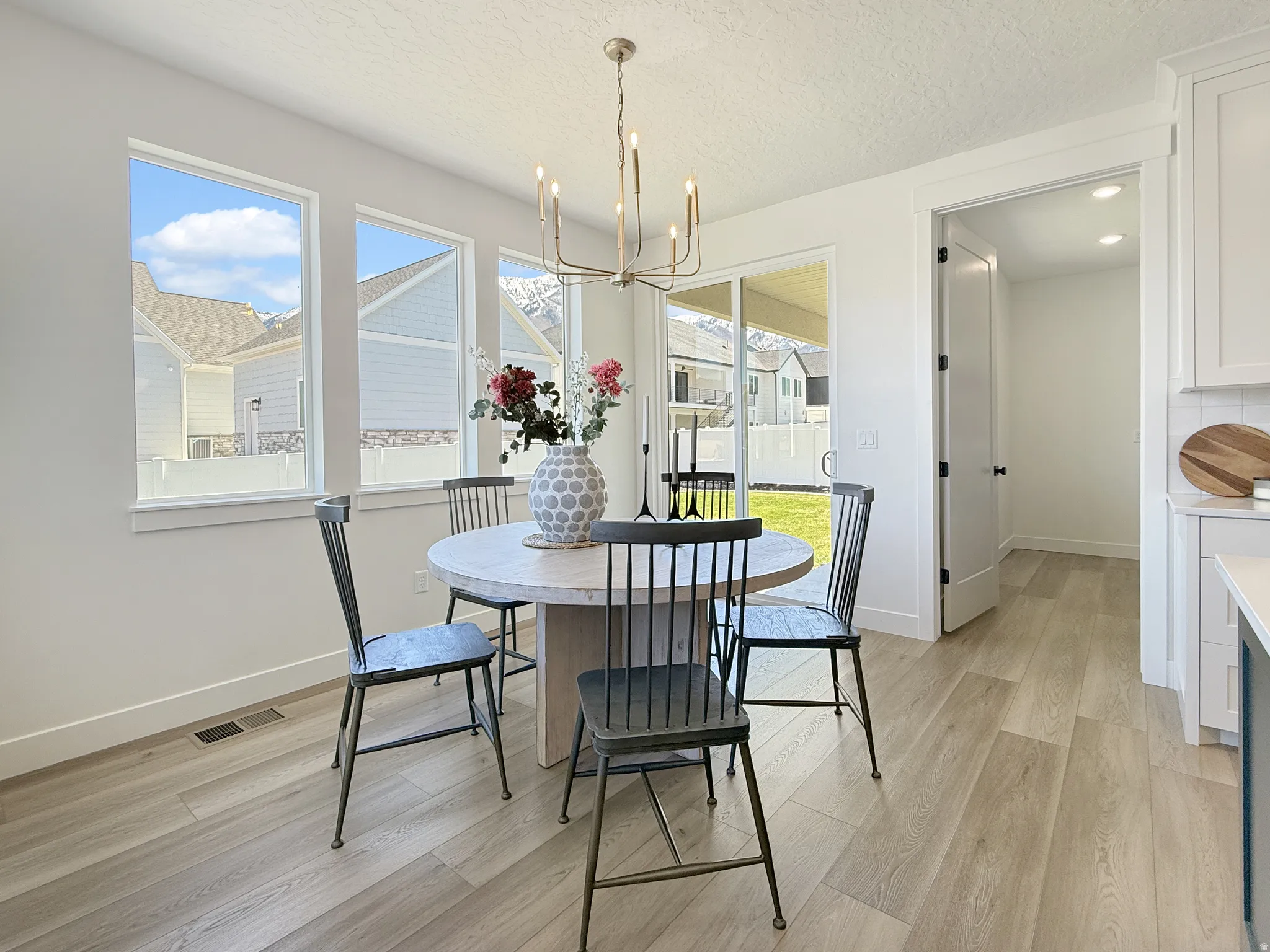 Dining room featuring light wood-style flooring, suspended lighting, healthy amount of natural light, and a textured ceiling