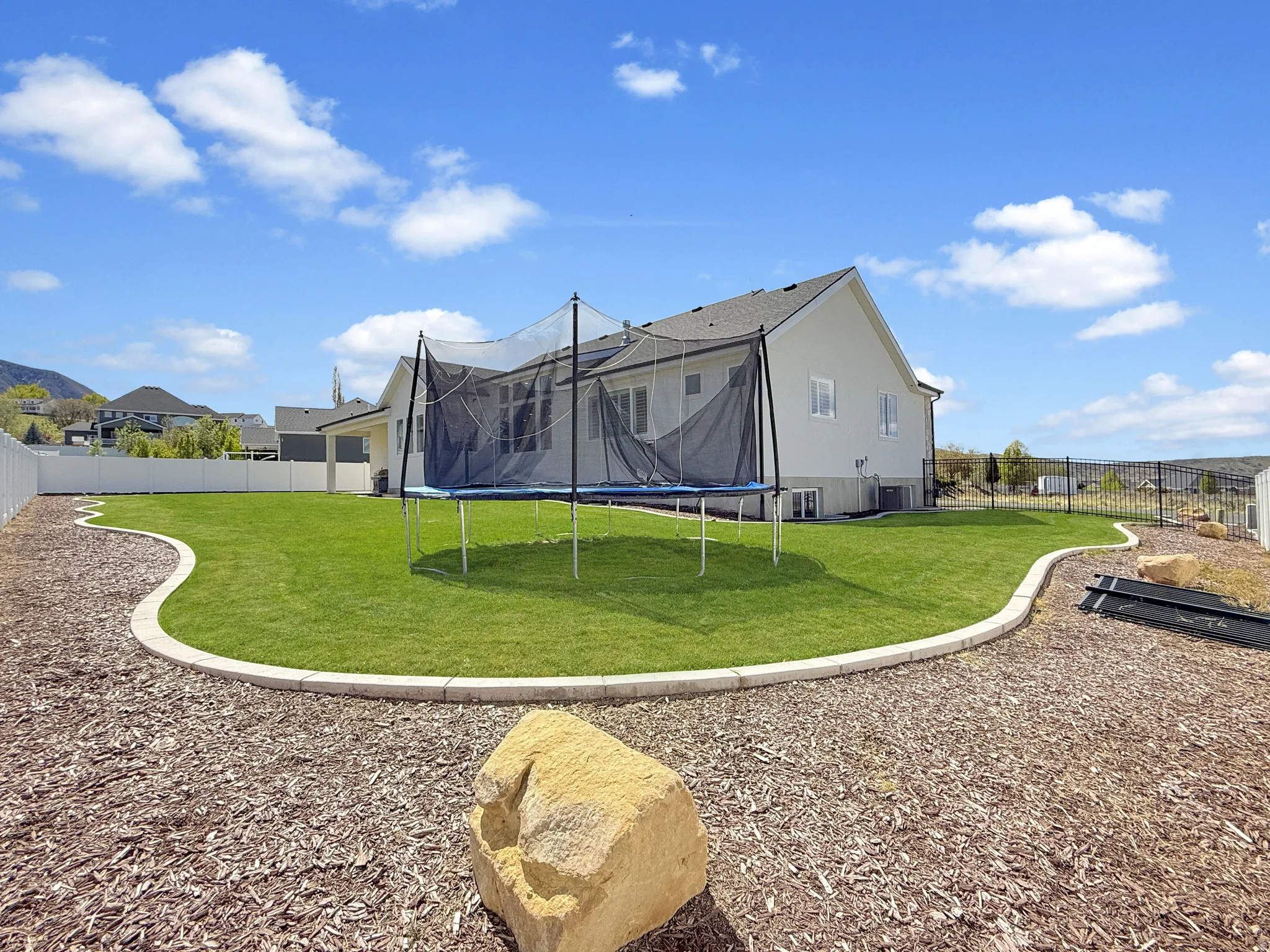 Rear view of house with a trampoline and a fenced backyard