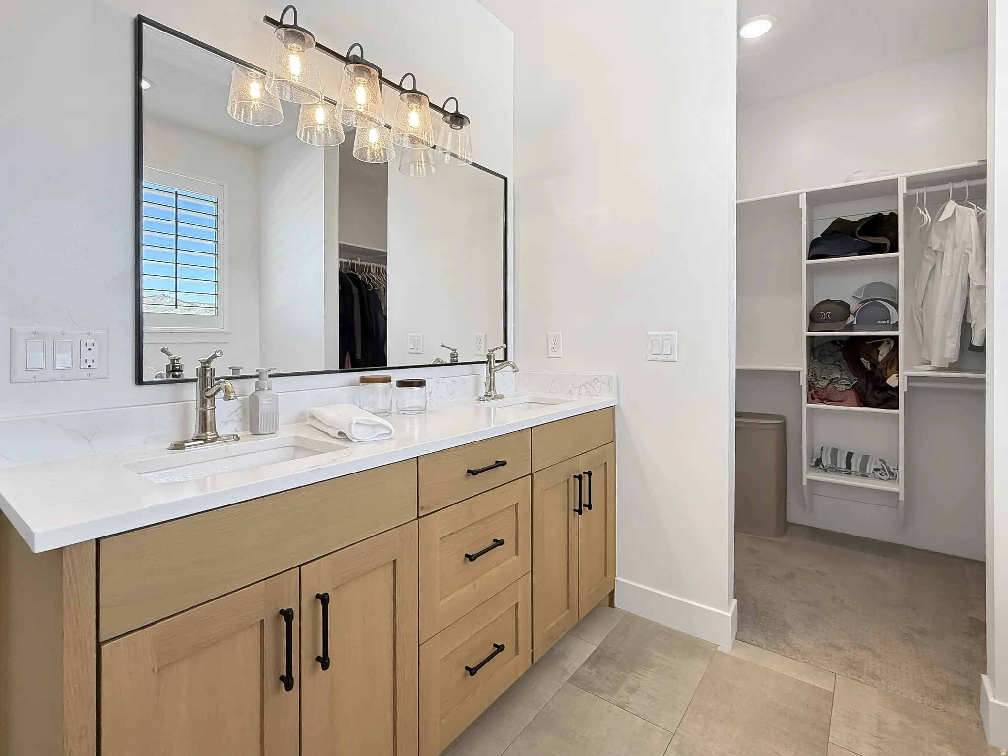 Bathroom with a spacious closet, double vanity, recessed lighting, light carpet, and light tile patterned floors