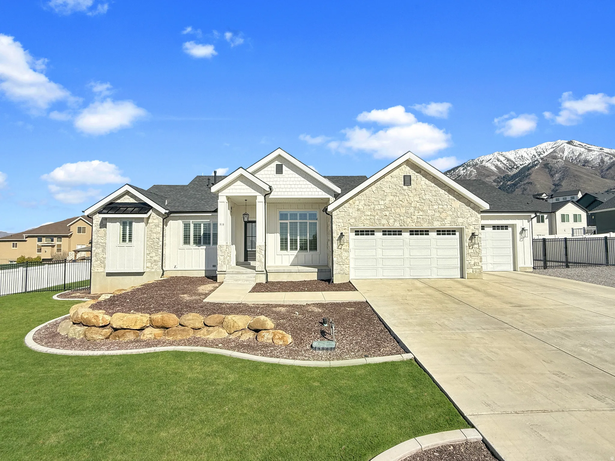 View of front of house with a garage, stone siding, driveway, board and batten siding, and a residential view
