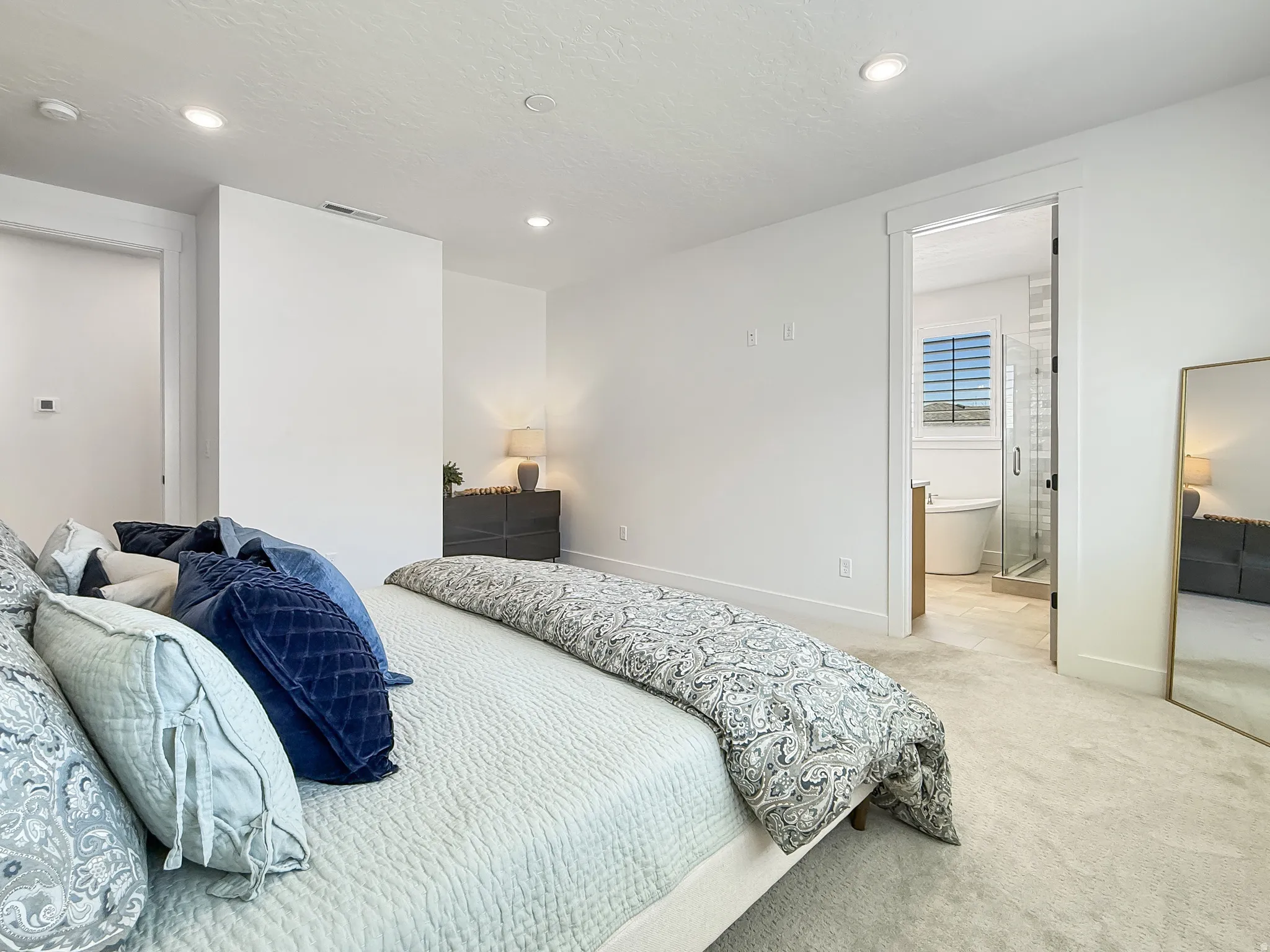Bedroom with light colored carpet, recessed lighting, a textured ceiling, and ensuite bath