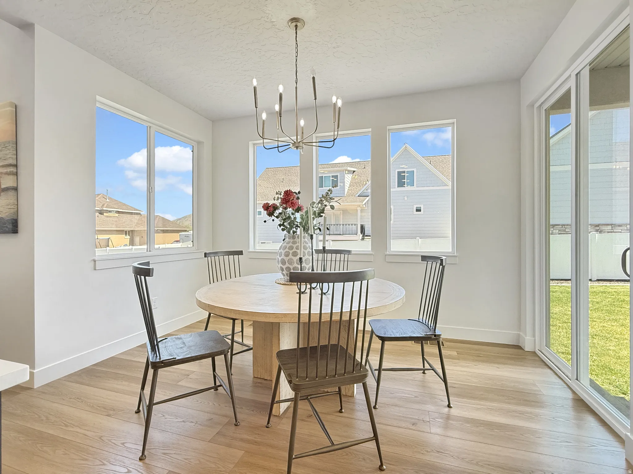 Dining space featuring suspended lighting, light wood finished floors, and a textured ceiling
