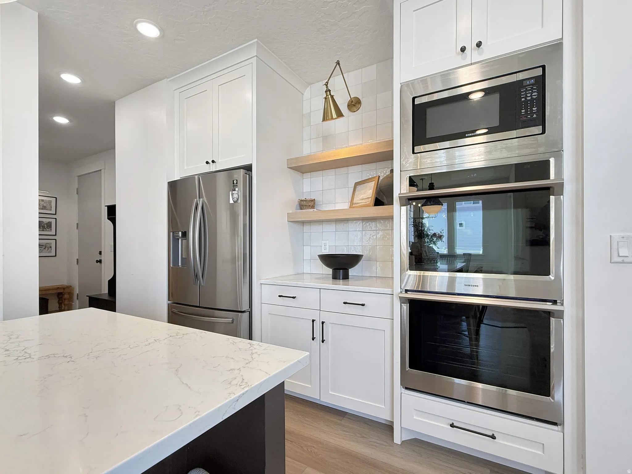 Kitchen with stainless steel appliances, white cabinets, backsplash, open shelves, and light wood-style floors