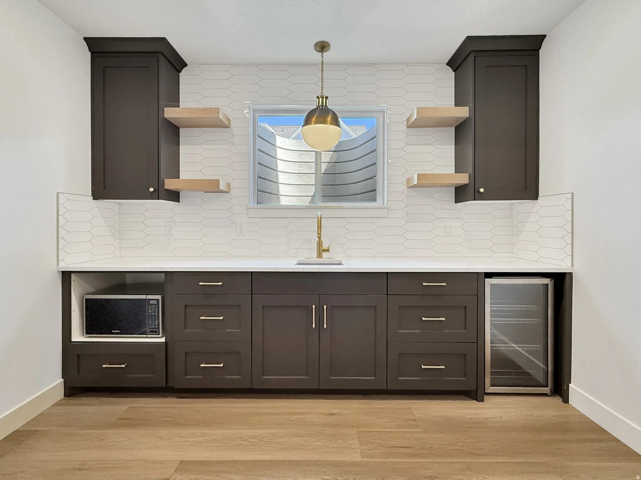 Kitchen with open shelves, wine cooler, decorative backsplash, light stone counters, and light wood finished floors
