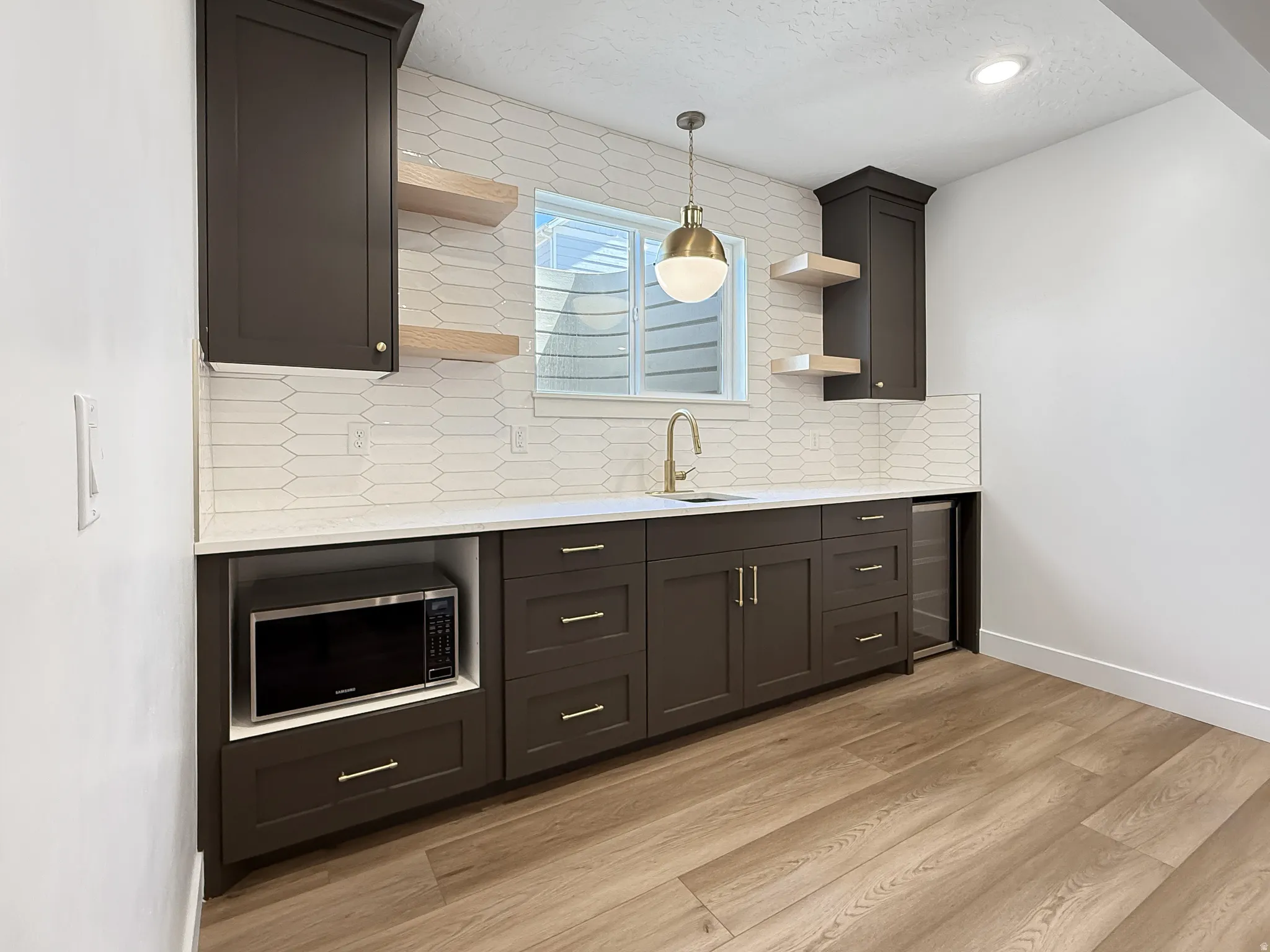 Kitchen featuring tasteful backsplash, light stone counters, decorative light fixtures, and open shelves