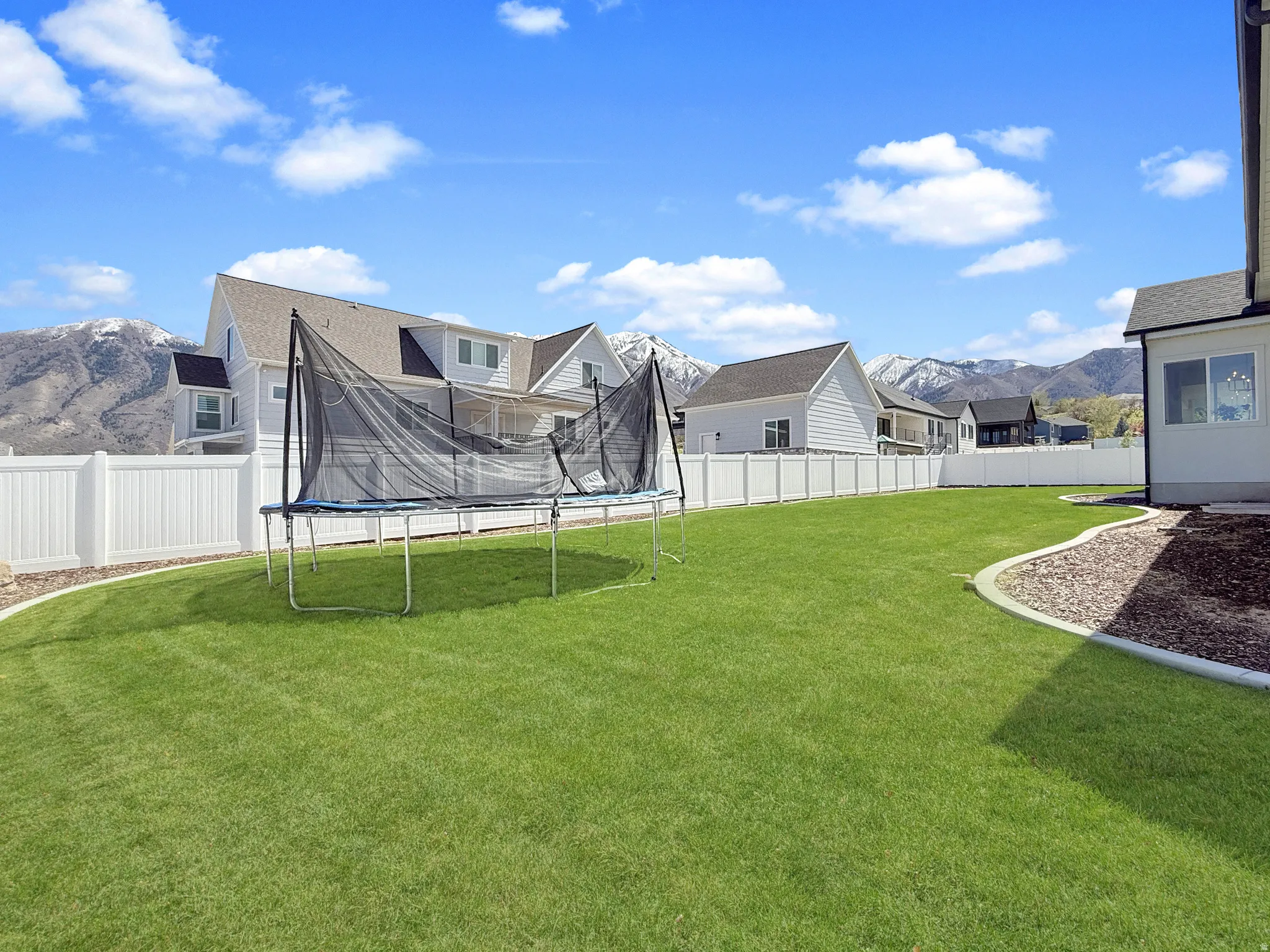 Fenced backyard featuring a mountain view and a trampoline