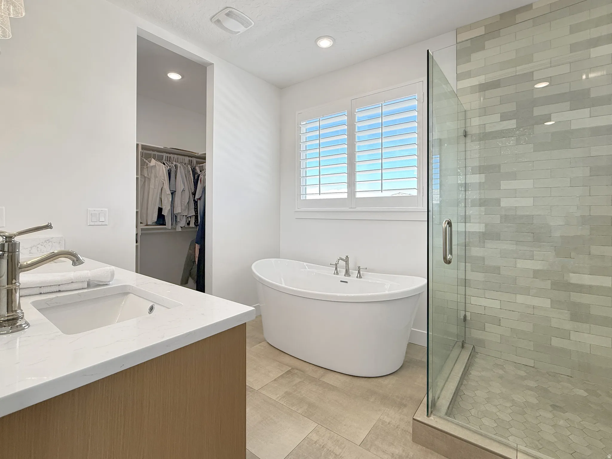 Bathroom featuring a shower stall, a soaking tub, recessed lighting, a walk in closet, and double vanity