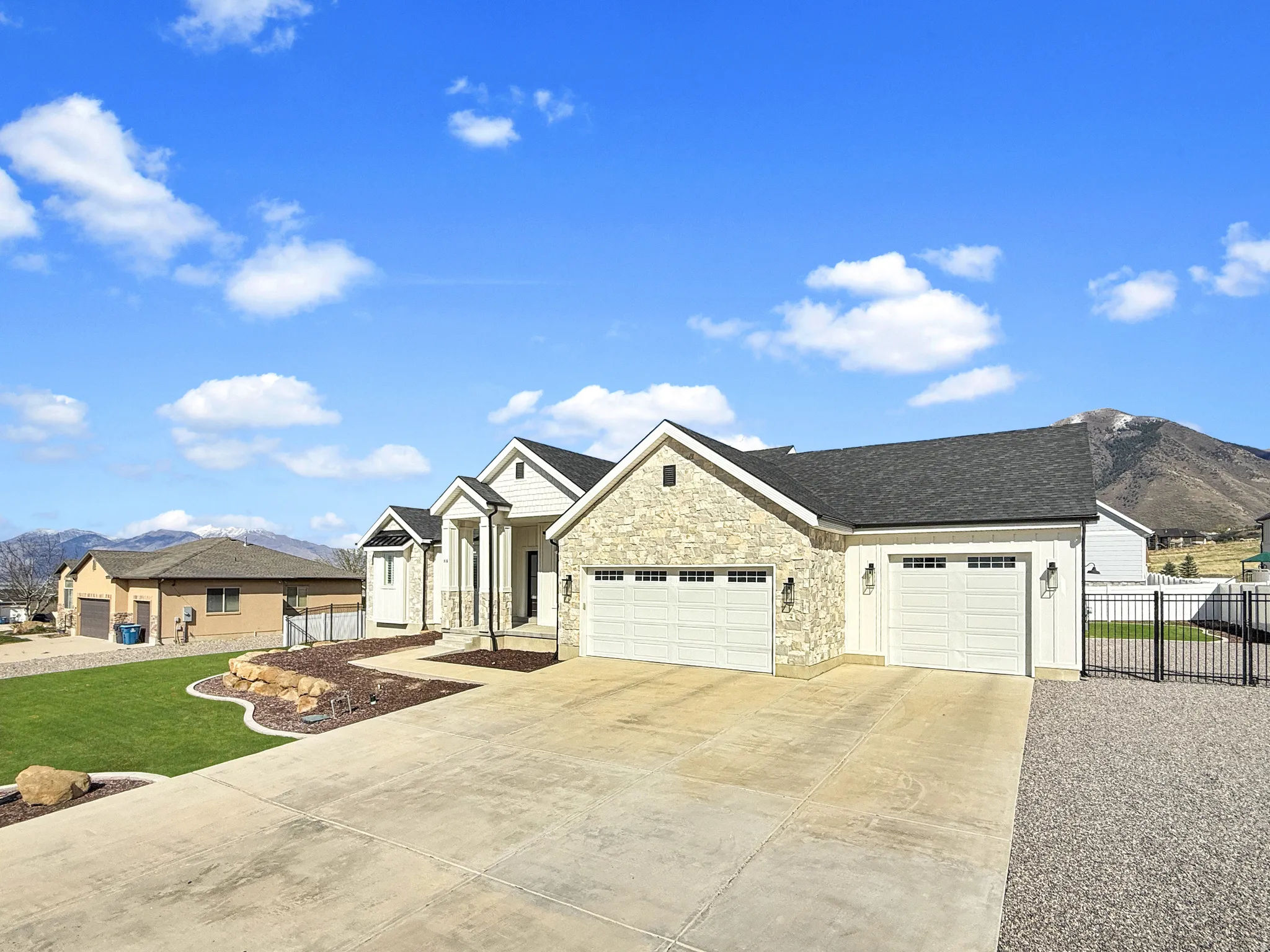 View of front of house featuring an attached garage, concrete driveway, a mountain view, stone siding, and a shingled roof