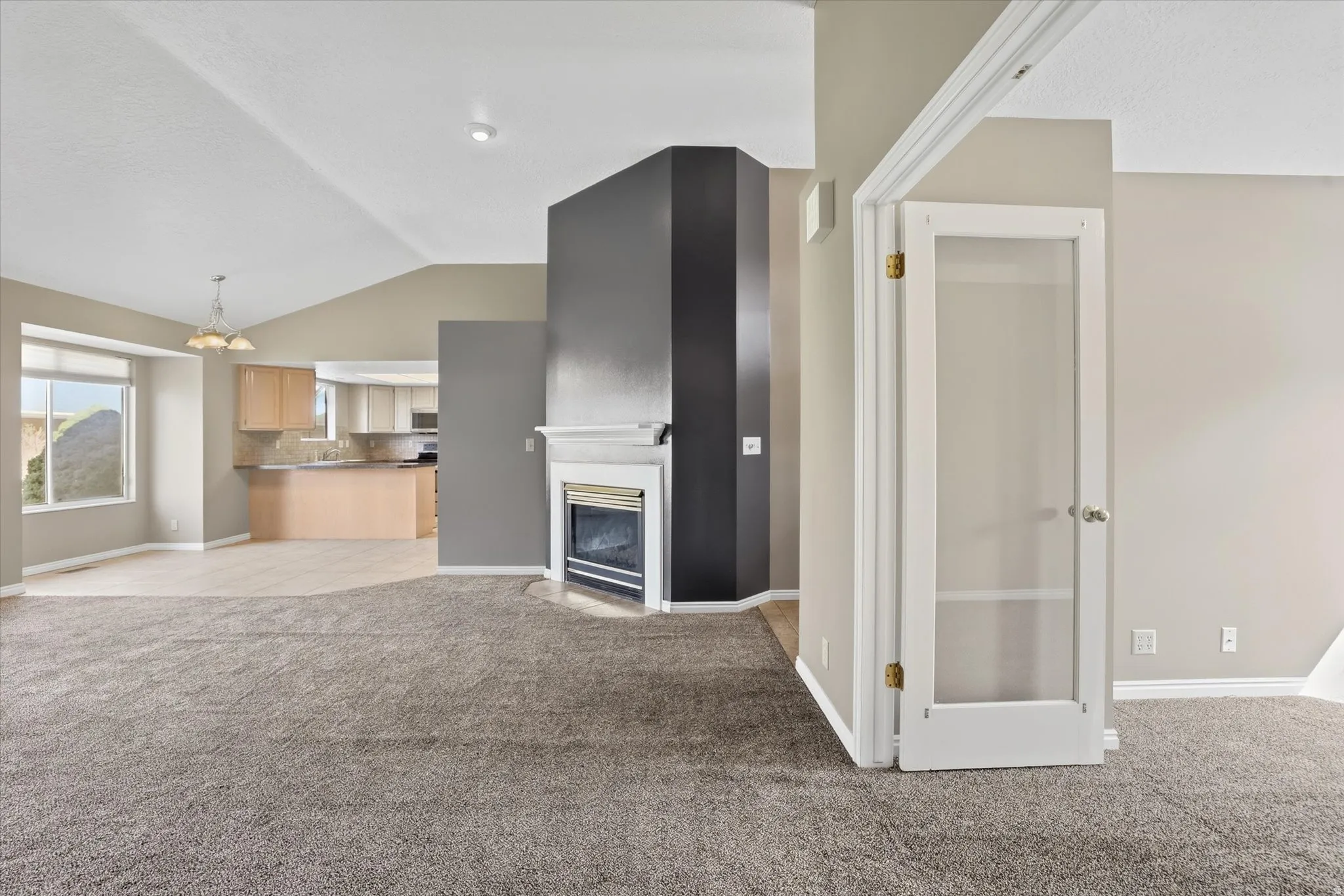 Living room featuring a gas fireplace, vaulted ceiling, and suspended lighting