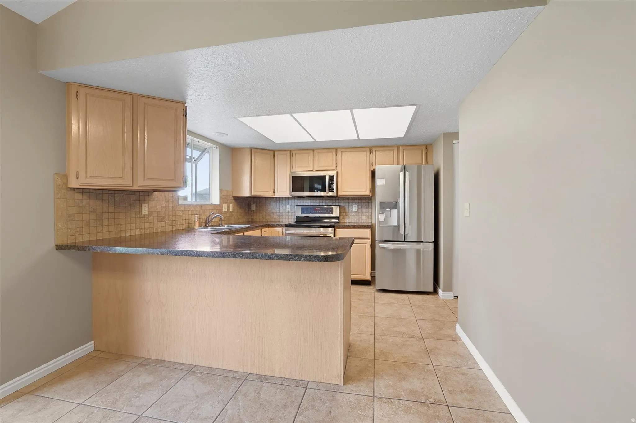 Kitchen featuring stainless steel appliances, wood finish cabinets, and decorative backsplash