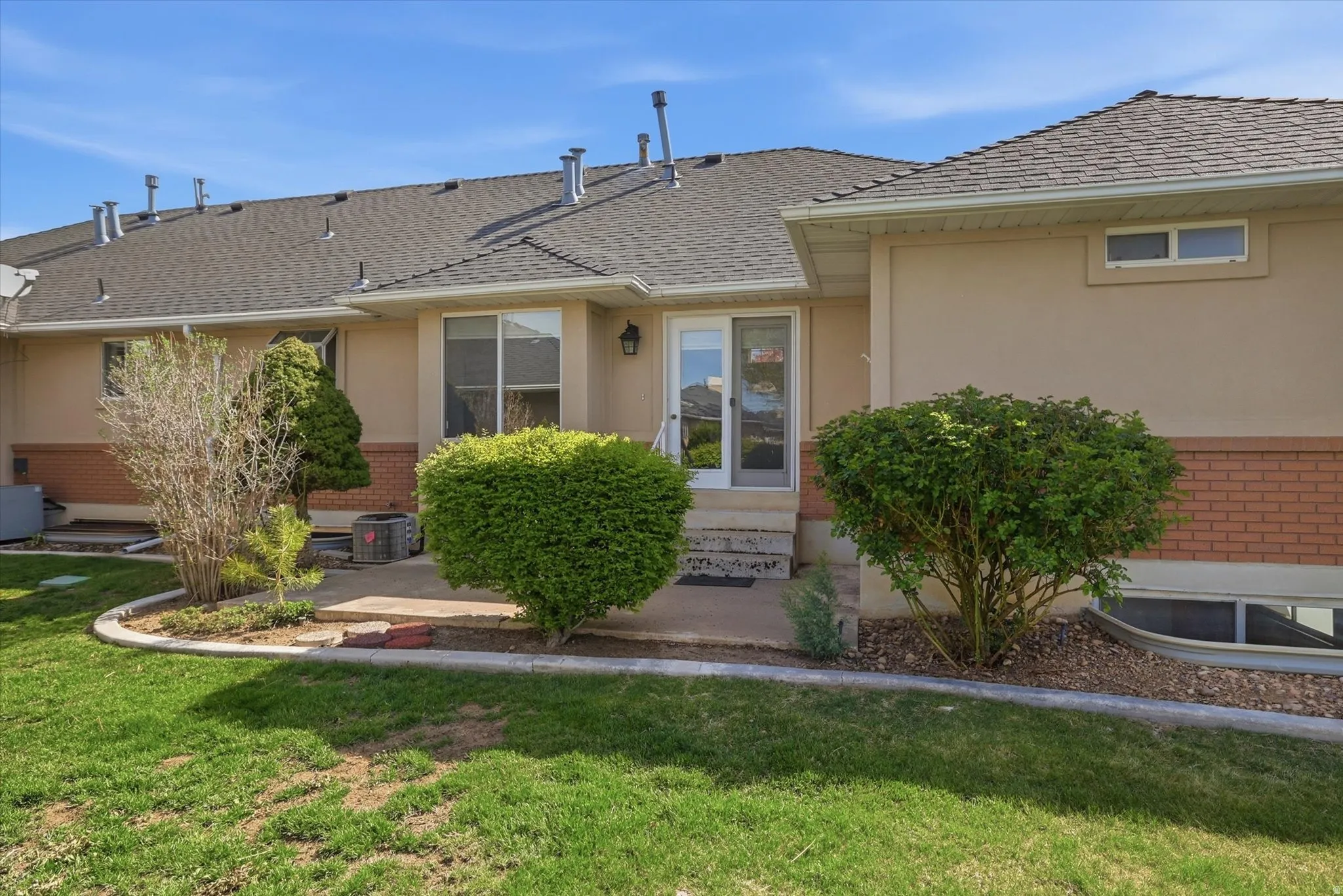 Rear view of house featuring brick , stucco, a patio and yard