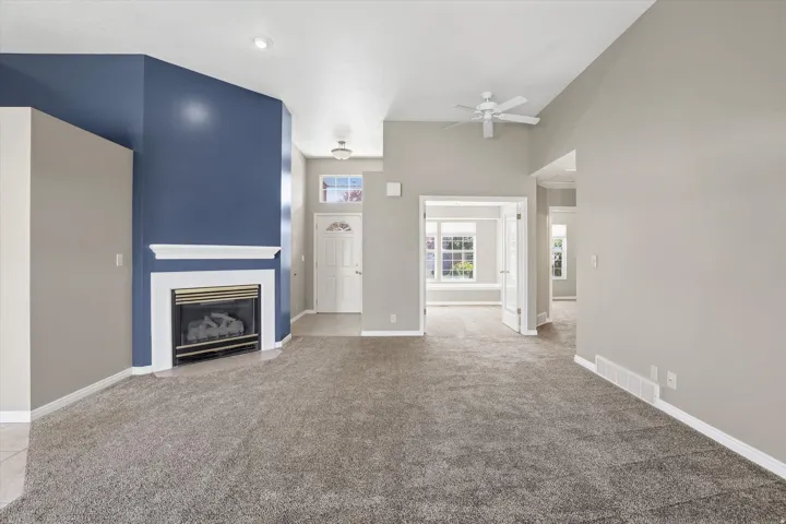 Living room with a ceiling fan, a fireplace with flush hearth, and a high ceiling