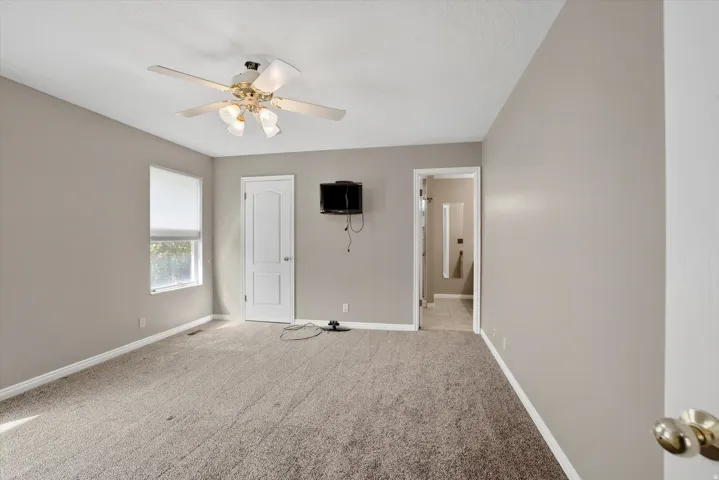 Primary bedroom with ceiling fan and private bathroom