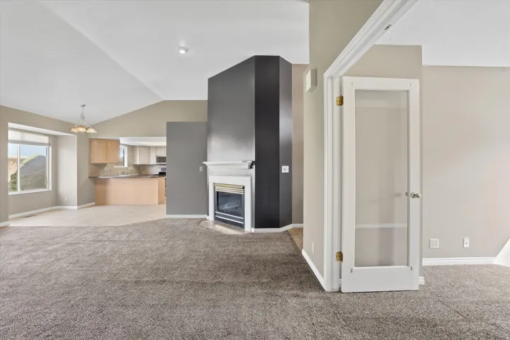 Living room featuring a gas fireplace, vaulted ceiling, and suspended lighting