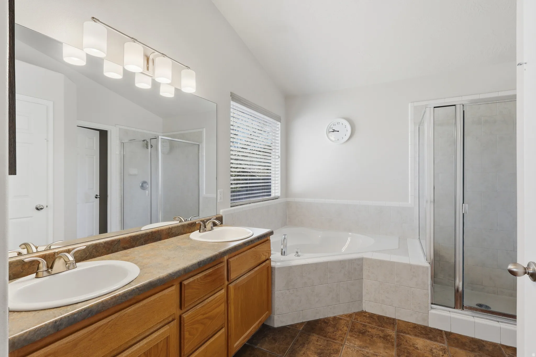 Large bathroom with double vanity, large garden tub & separate shower, lofted ceiling, & picture window.