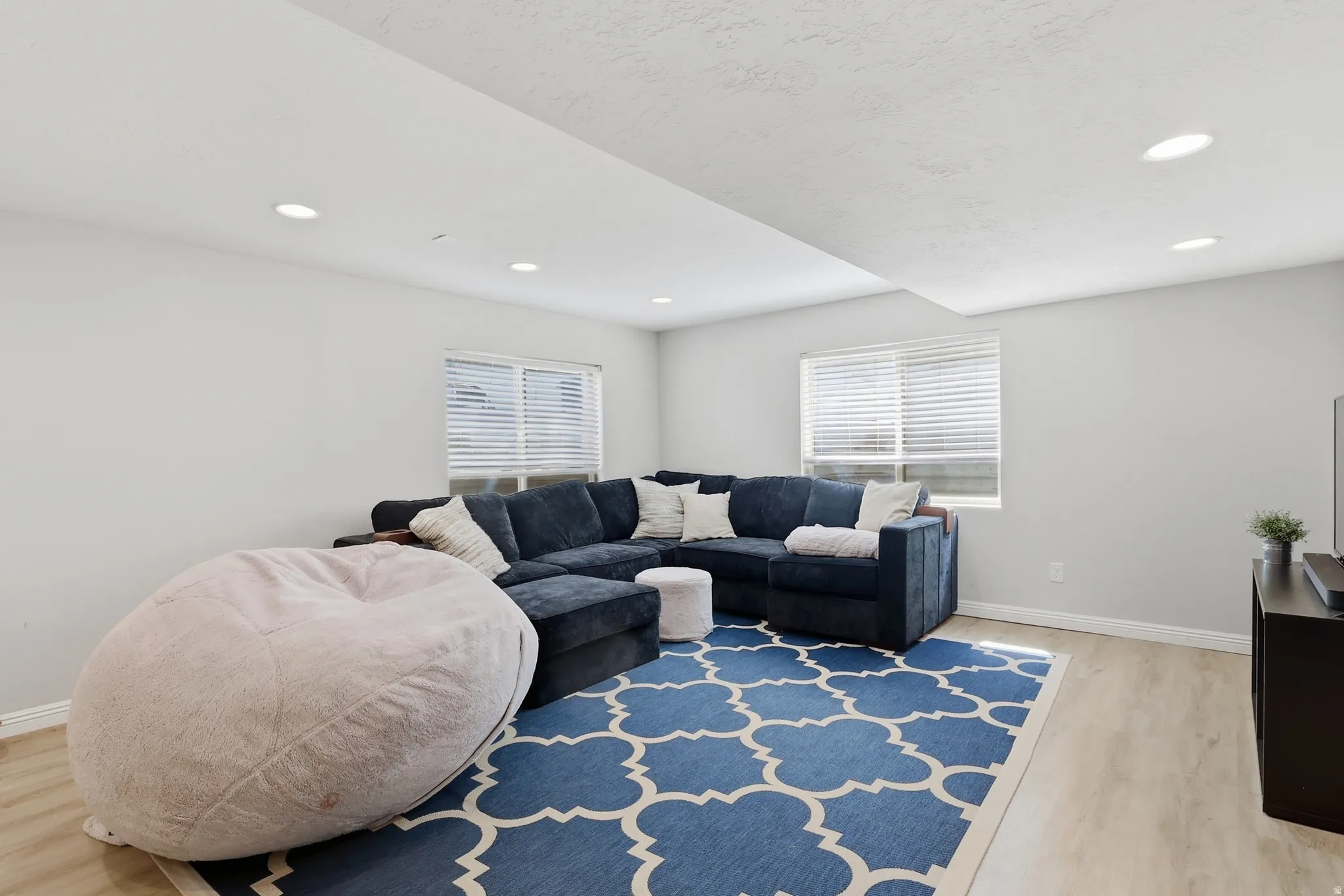 Living area with light wood finished floors, healthy amount of natural light, and recessed lighting