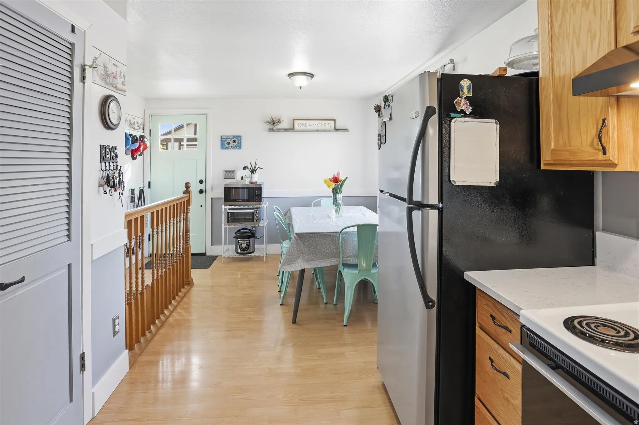 Kitchen featuring white stove, wood finish cabinetry, light wood-style flooring, and stainless steel microwave