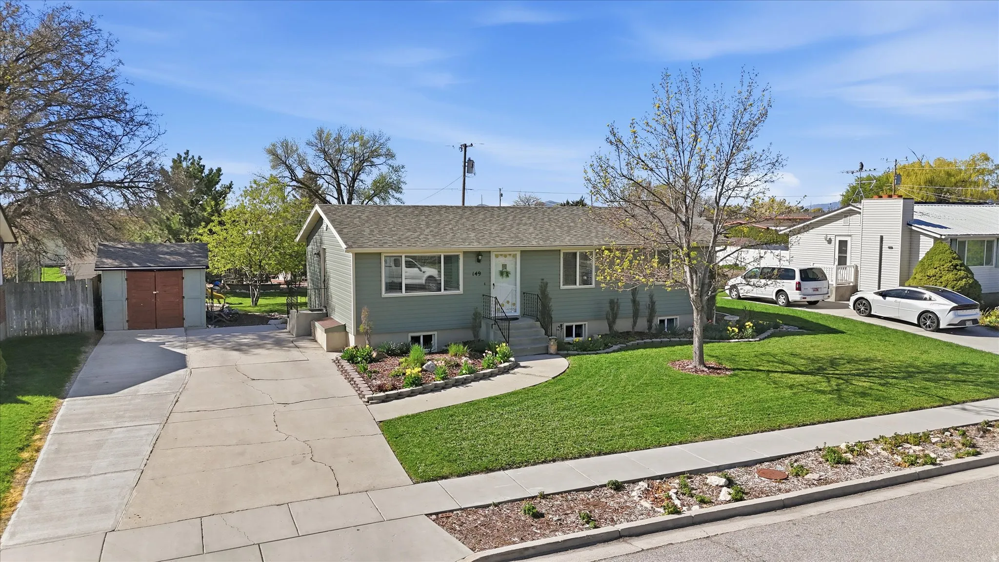 View of front of home featuring driveway, a storage unit, and roof with shingles