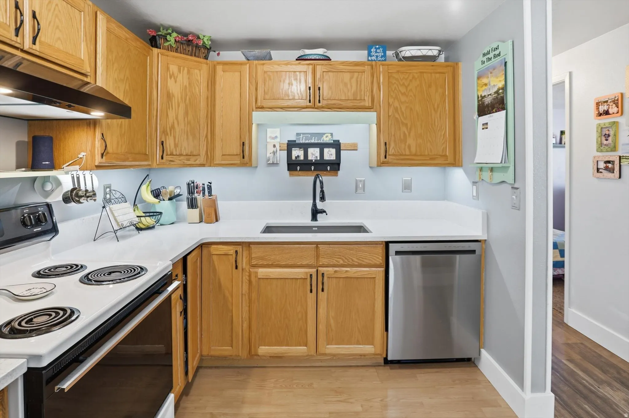 Kitchen featuring electric range, dishwasher, light wood-type flooring, and open shelves
