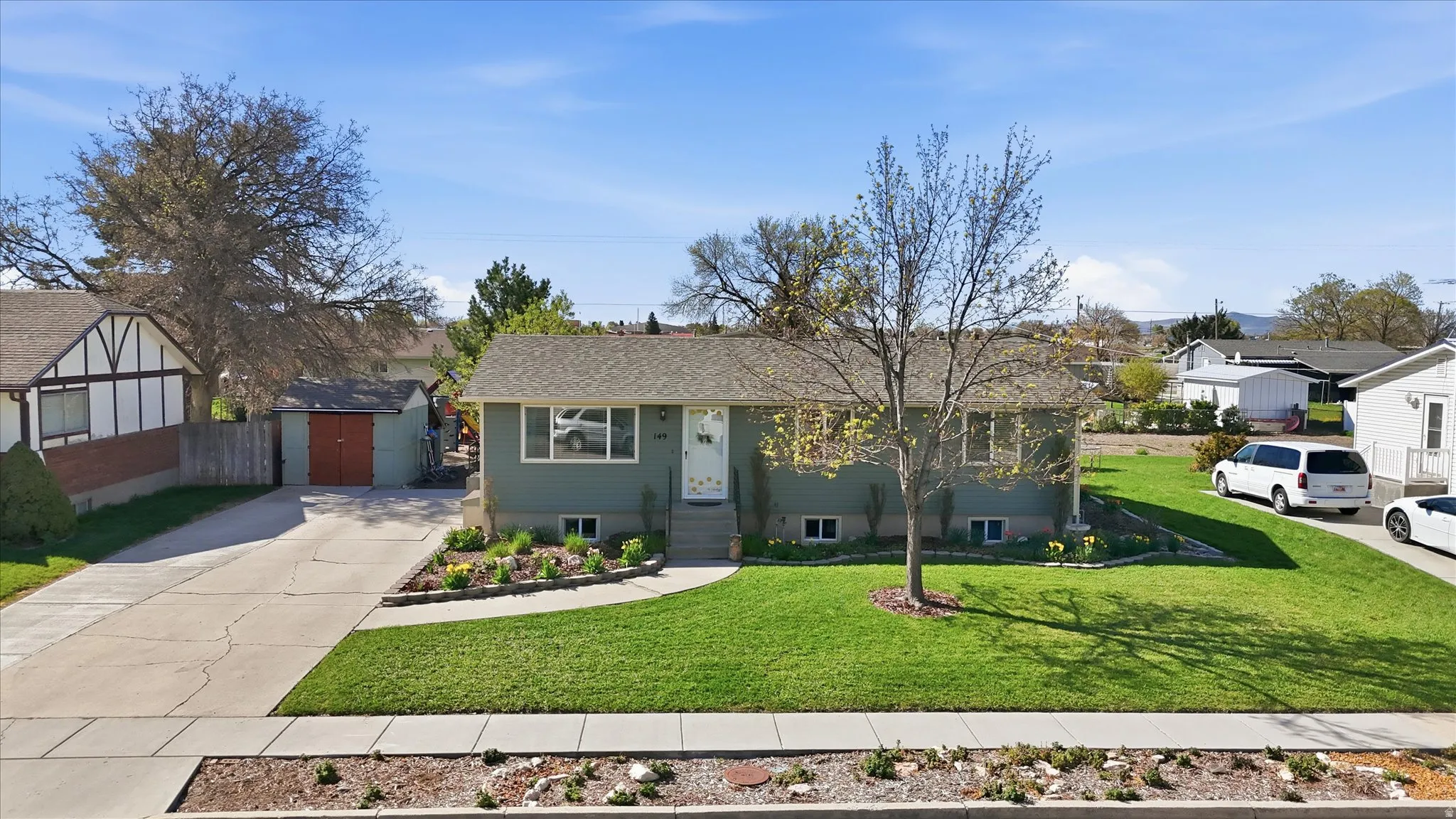 Ranch-style house with driveway, a front yard, an outbuilding, and a residential view