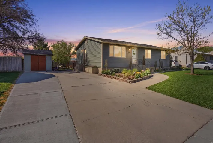 View of front facade with concrete driveway and a storage shed