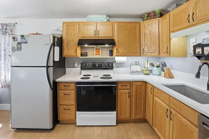 Kitchen featuring white appliances, light stone counters, and light wood-style floors
