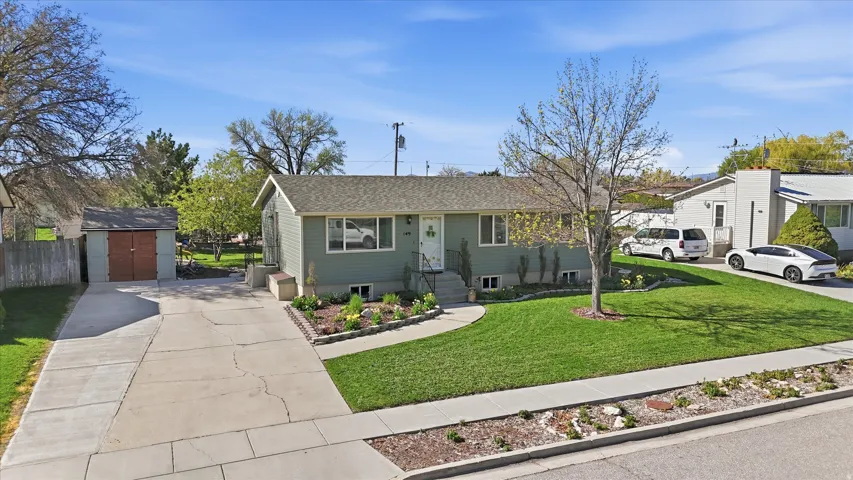 View of front of home featuring driveway, a storage unit, and roof with shingles