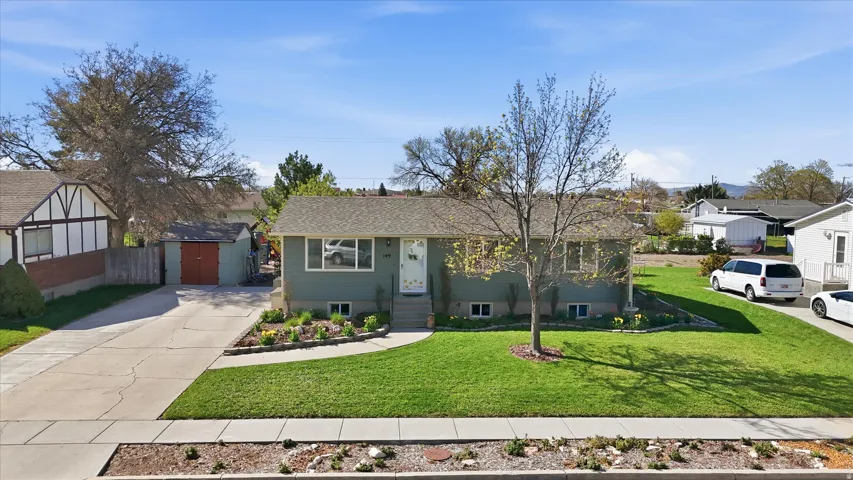 Ranch-style house with driveway, a front yard, an outbuilding, and a residential view