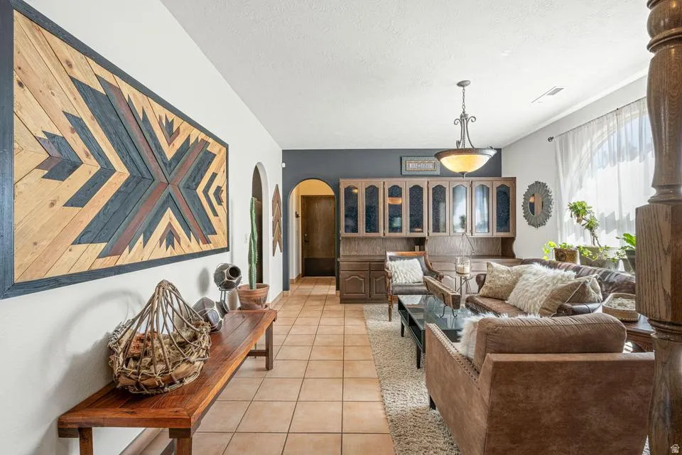 Living room featuring arched walkways, light tile patterned flooring, and a textured ceiling