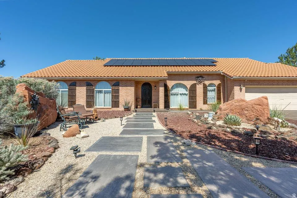 Mediterranean / spanish-style house featuring solar panels, brick siding, a tiled roof, and a garage