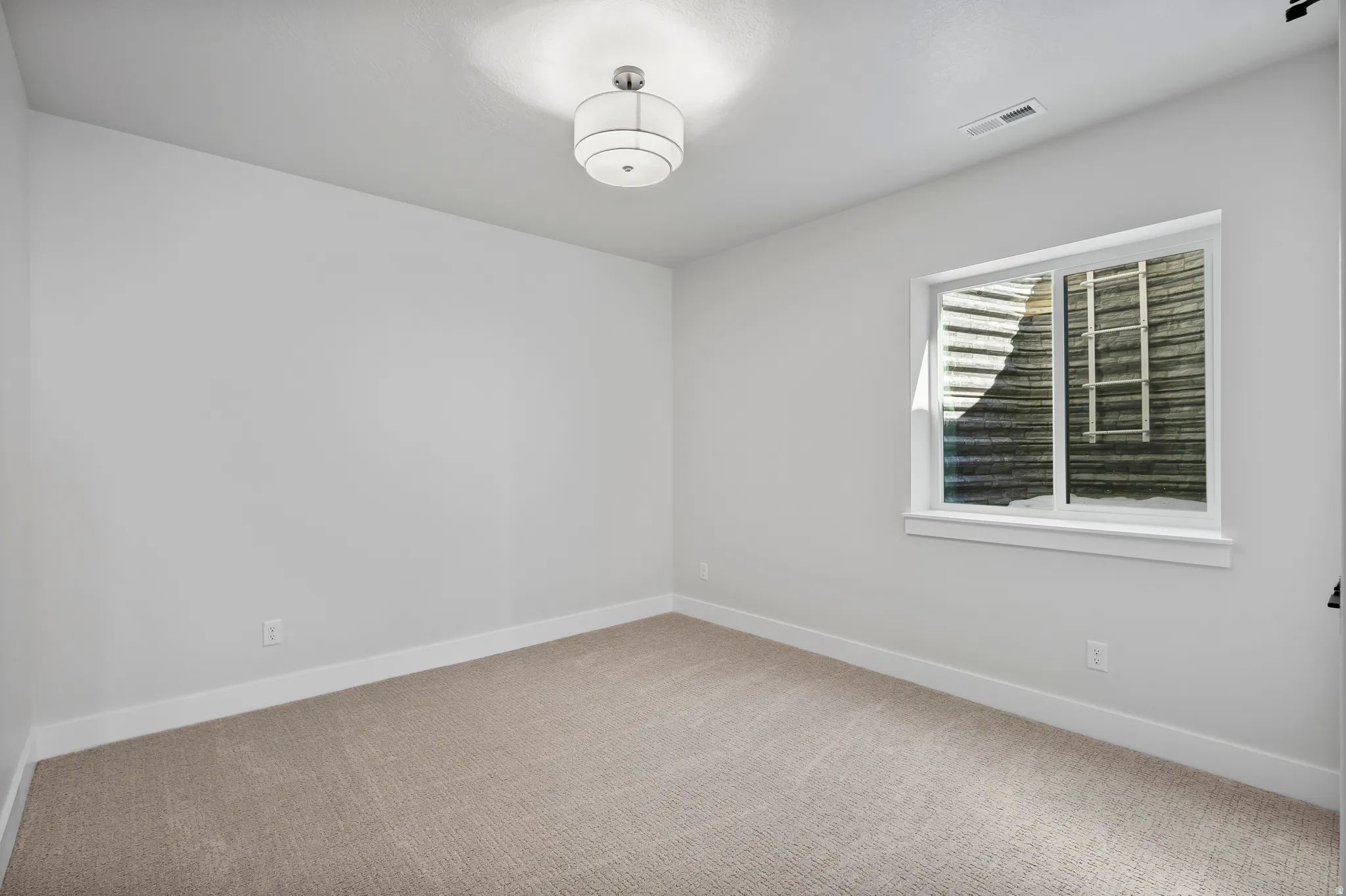 Neutral tone wall paint, light-colored carpeting, white trim, recessed lighting, and a window with white casing