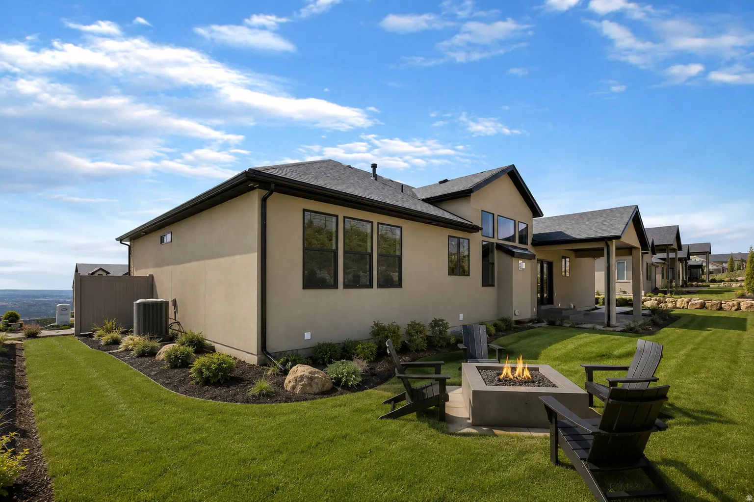 Rear exterior featuring a built-in fire pit, covered patio, manicured lawn, and multiple windows