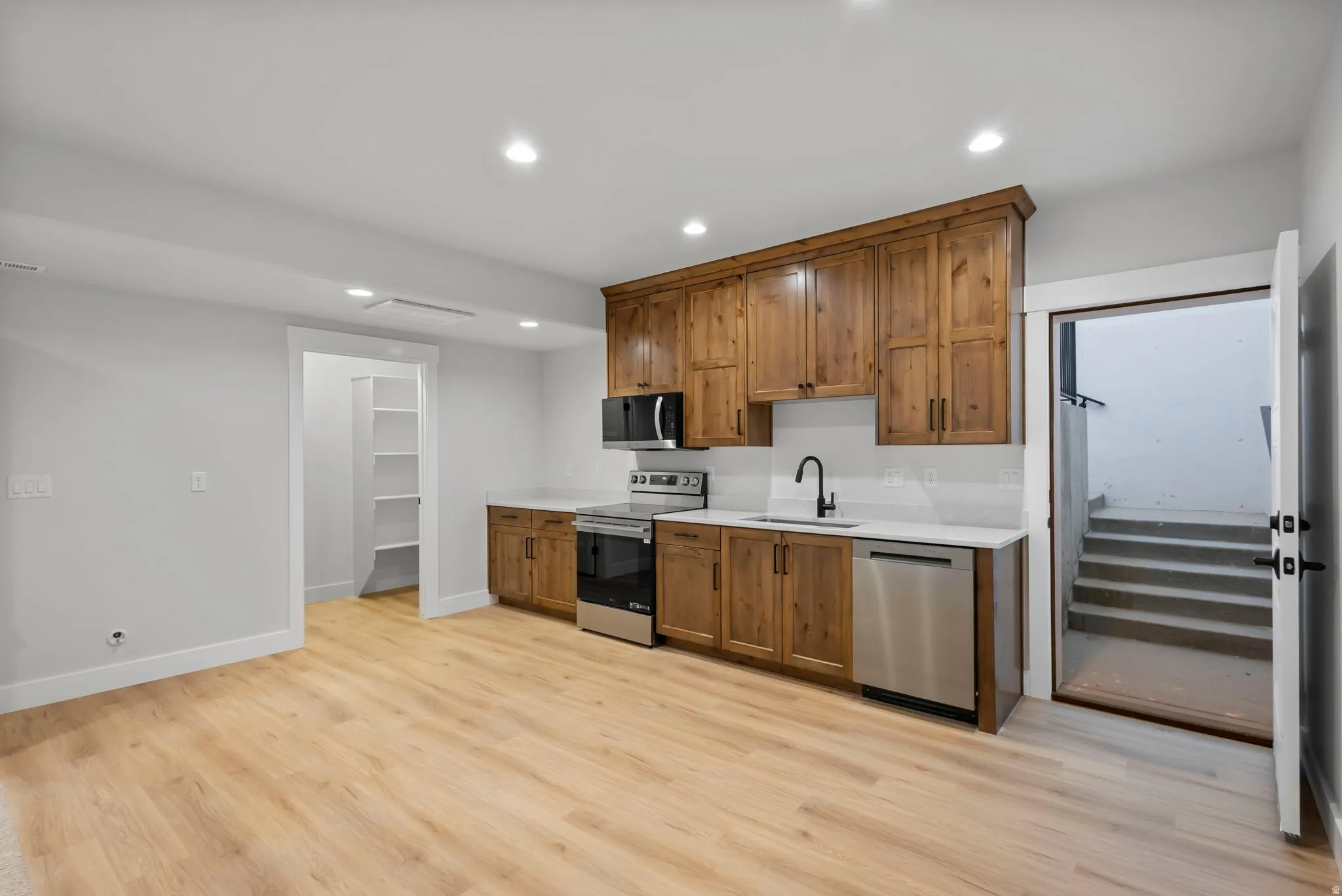 Kitchen with stainless steel appliances, wood finish cabinets, recessed lighting, and light wood-type flooring