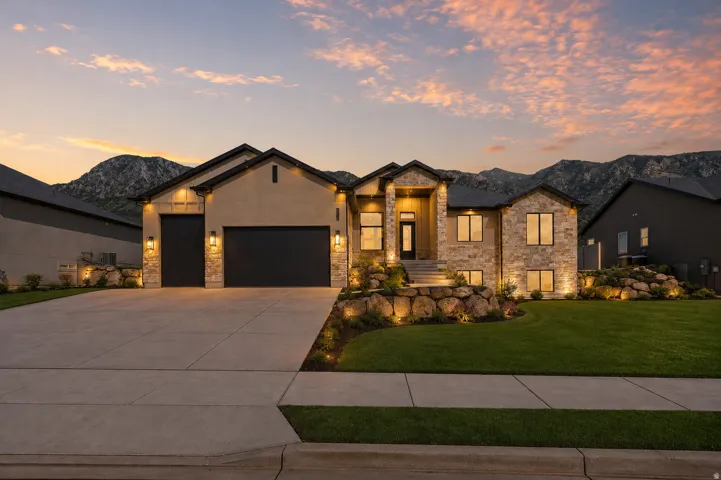Ranch-style house with an attached garage, driveway, stone siding, and a mountain view