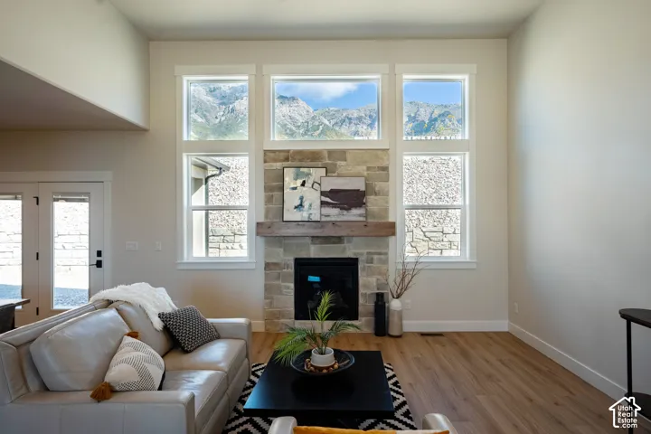 Living area with a stone-clad fireplace, wood-finish flooring, and high ceilings