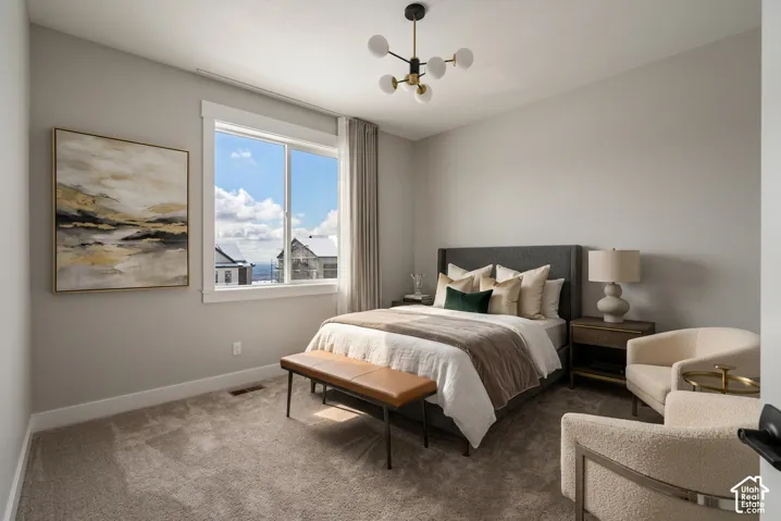 Carpeted bedroom featuring a large window, a fabric upholstered headboard, and a contemporary ceiling light fixture