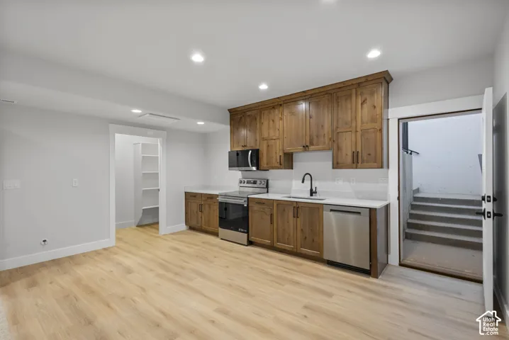 Kitchen with stainless steel appliances, wood finish cabinets, recessed lighting, and light wood-type flooring